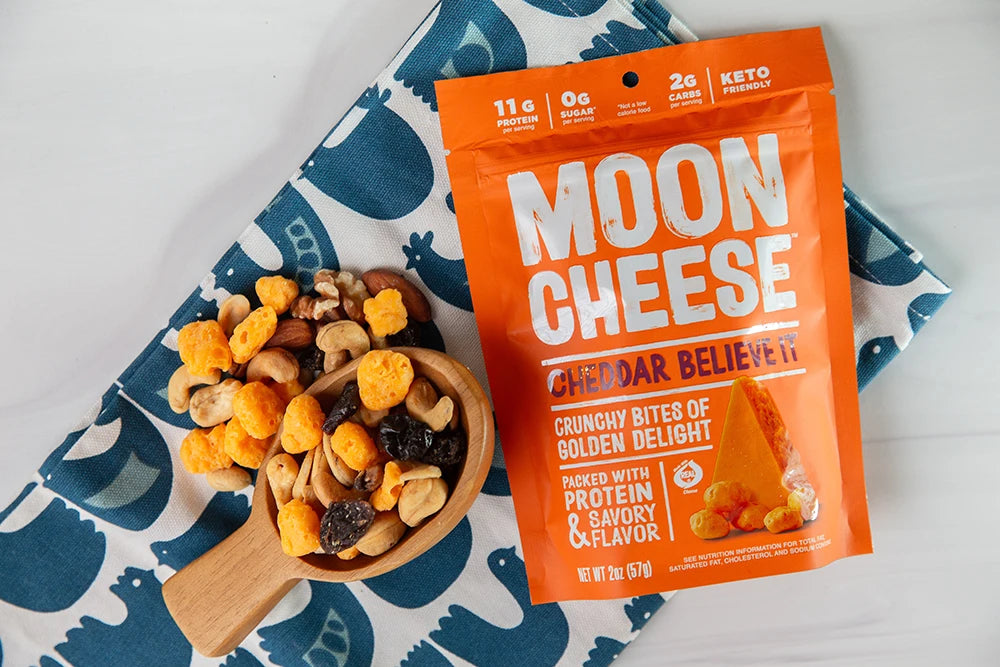 gluten free sugar free keto friendly high protein cheddar believe it moon cheese with trail mix and the package on a colorful napkin