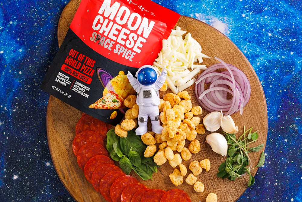 gluten free sugar free keto friendly high protein out of this world pizza moon cheese with pizza ingredients on a snack board with an astronaut on a starry background