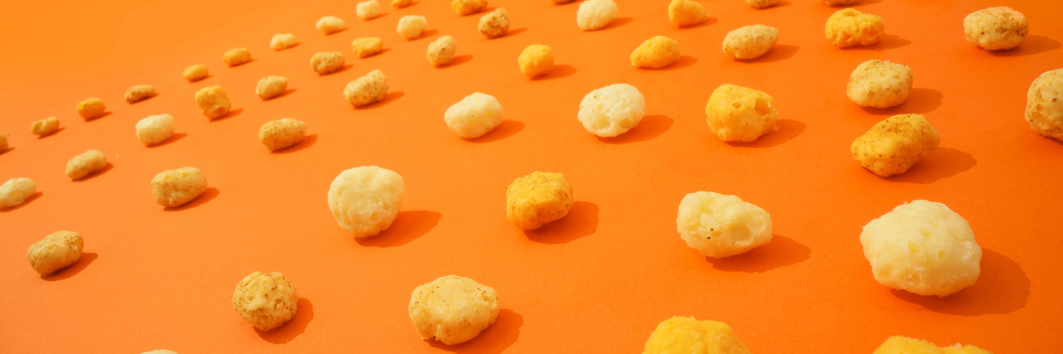 Assorted gluten free sugar free keto friendly high protein moon cheese in lines across an orange background